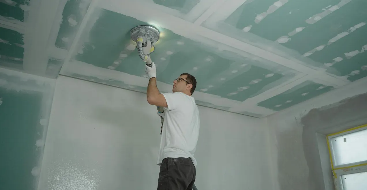 Finishing a drywall ceiling with a taping knife.